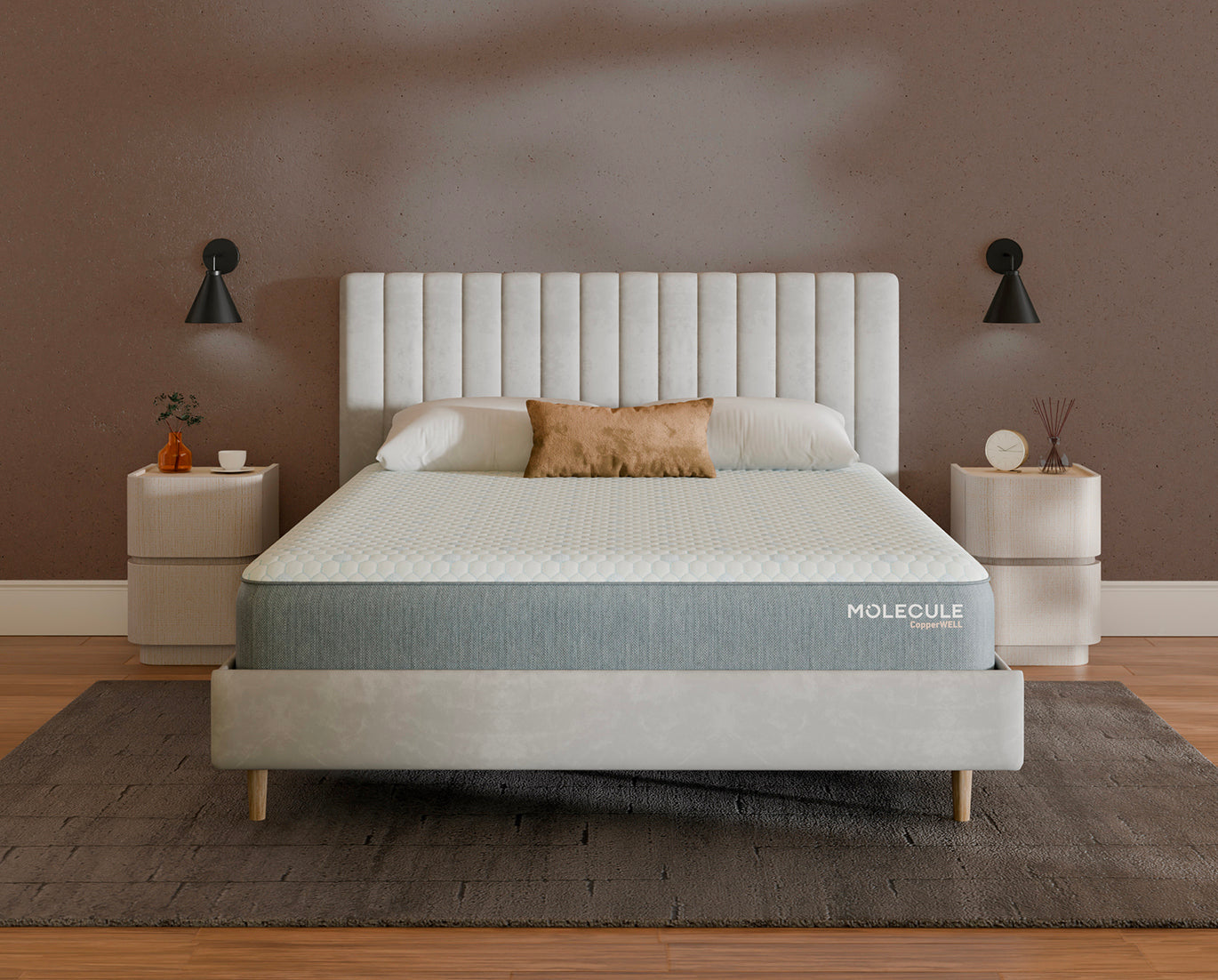 A bed with a white tufted headboard and mattress featuring a blue-gray side panel labeled 'MOLECULE comfort', styled in a bedroom with matching nightstands, wall lamps, and a textured rug.