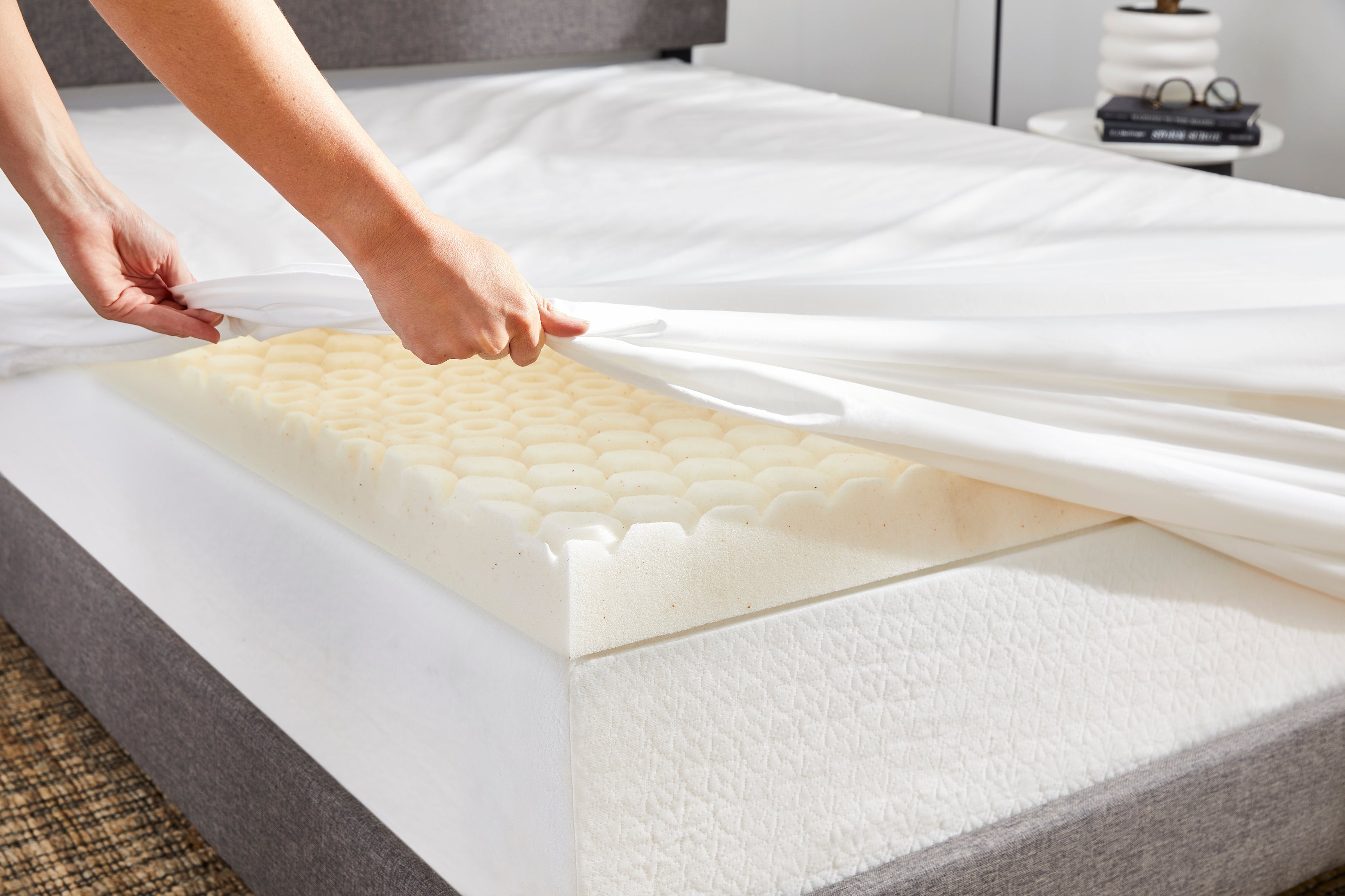 Woman covering a Molecule bed topper with Molecule sheets